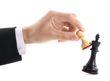 Photo of Man with white pawn knocking over chess king on white background, closeup. Competition concept