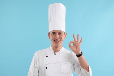 Photo of Professional chef showing okay gesture on light blue background