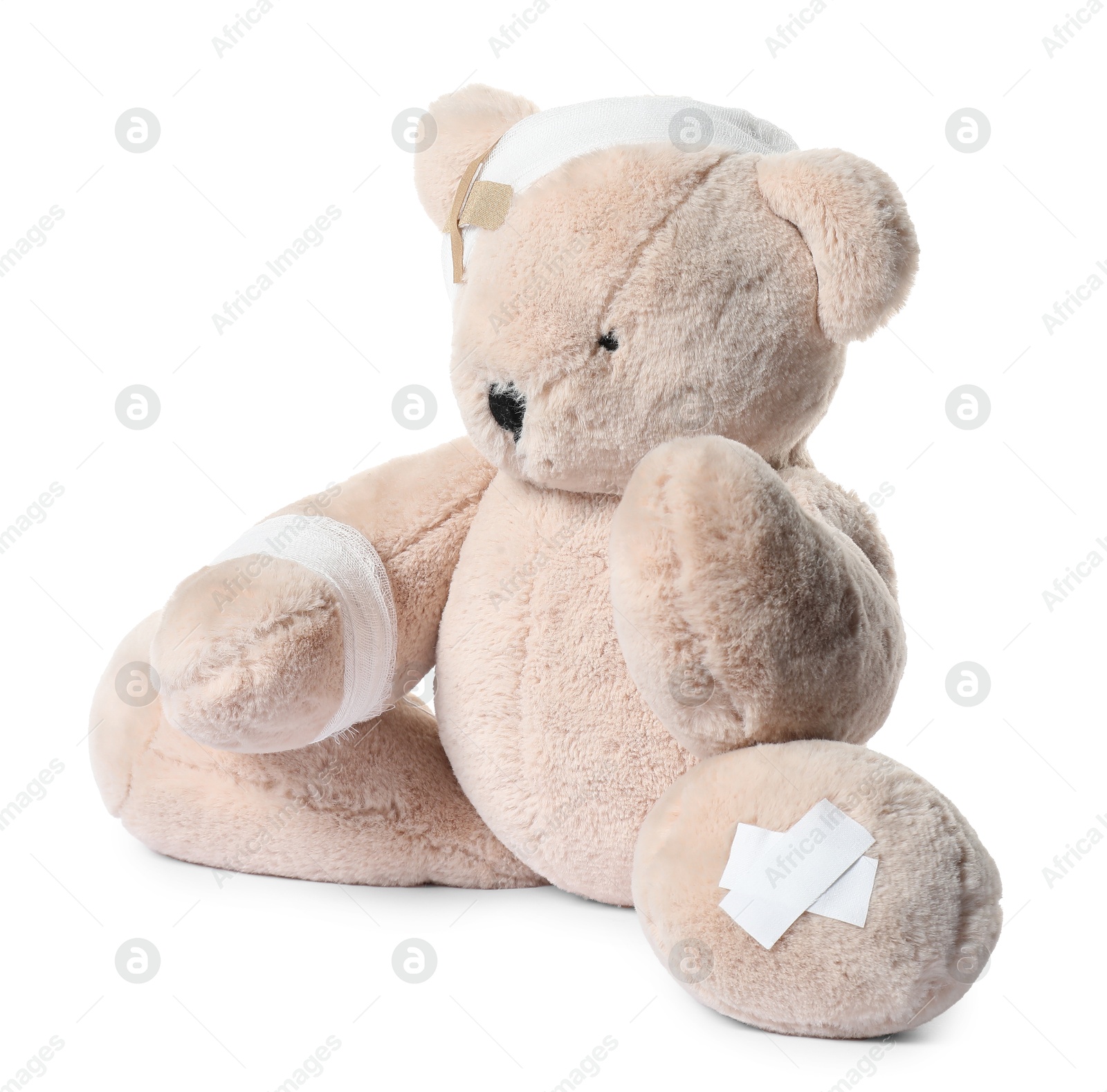 Photo of Teddy bear with bandages and adhesive medical plasters isolated on white