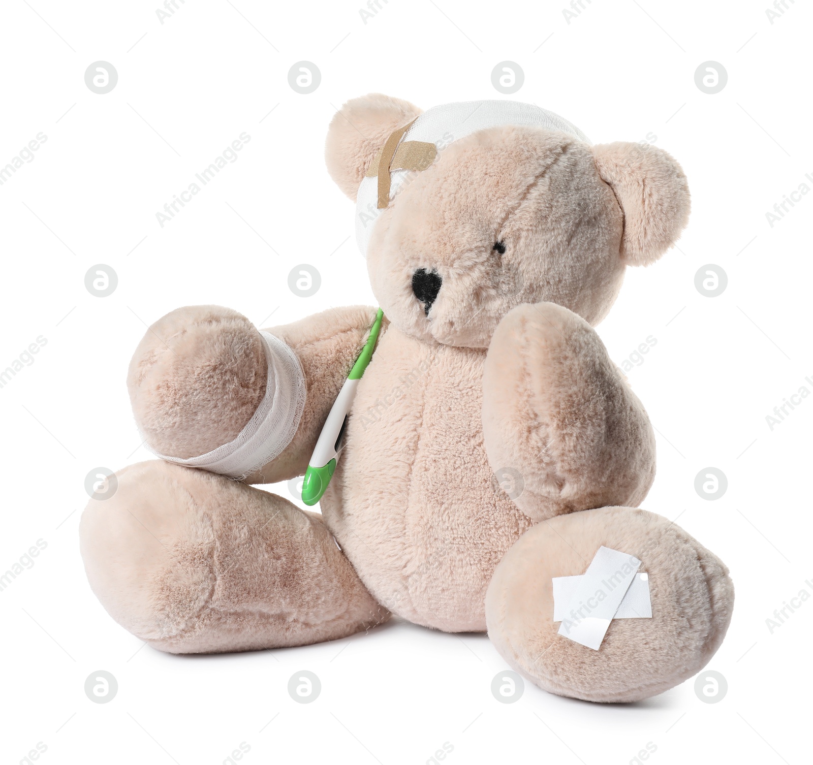 Photo of Teddy bear with bandages, adhesive medical plasters and thermometer isolated on white