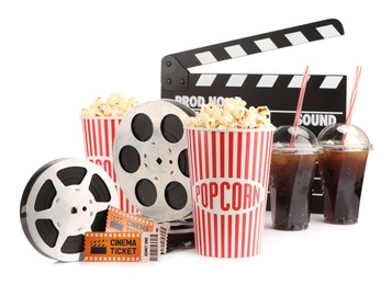 Photo of Tasty popcorn, film reels, clapper, soda drinks and movie tickets isolated on white