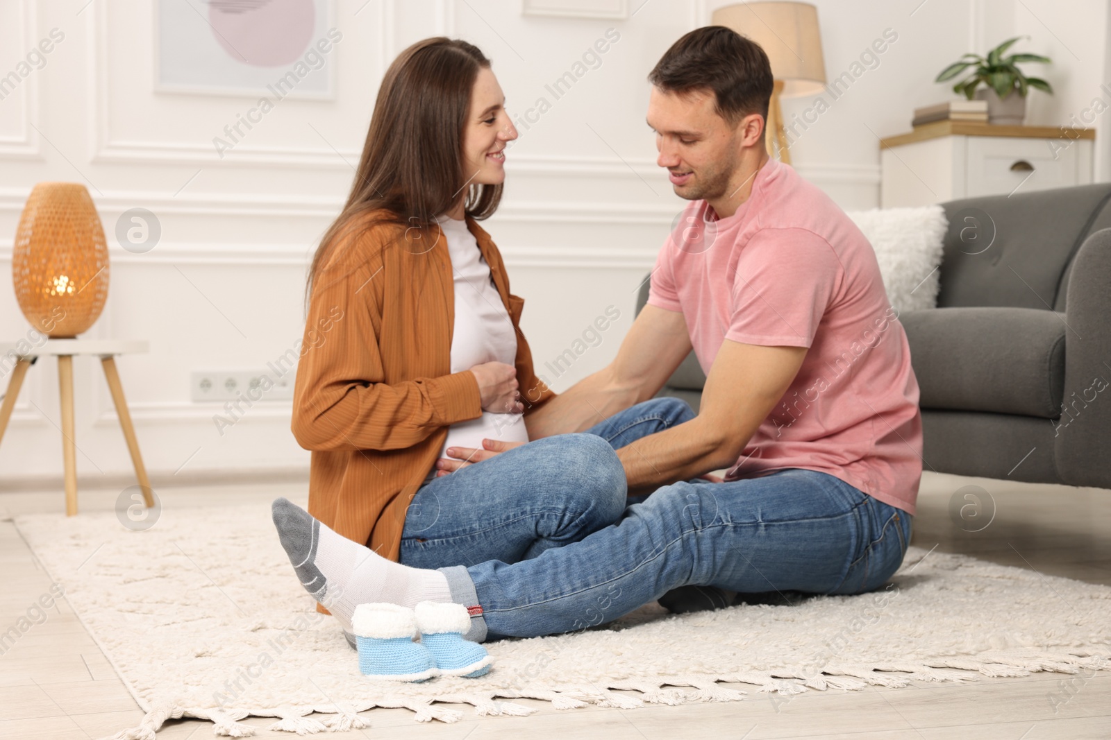 Photo of Man trying to feel baby kicks in his pregnant wife's belly at home