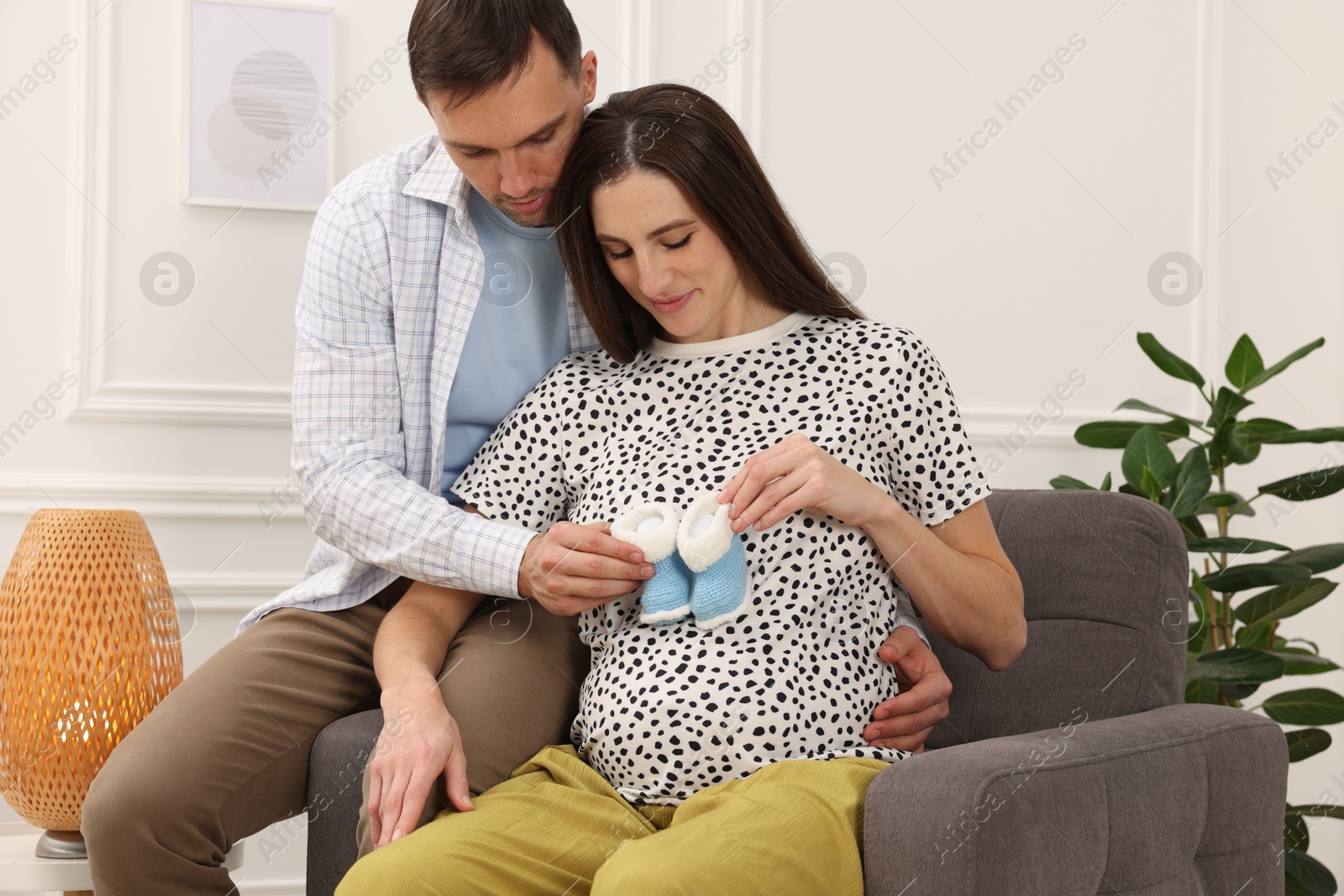 Photo of Pregnant woman and her husband with baby booties at home