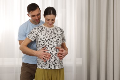 Photo of Pregnant woman and her husband at home. Space for text