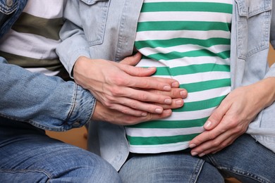 Photo of Pregnant woman and her husband on beige background, closeup