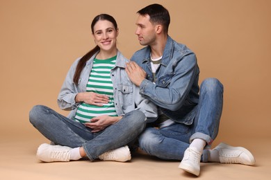 Photo of Pregnant woman and her husband on beige background