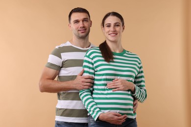 Photo of Pregnant woman and her husband on beige background