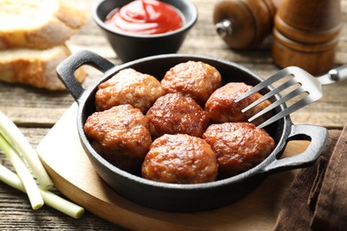 Photo of Tasty meatballs in baking dish served on wooden table, closeup