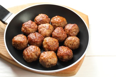 Photo of Tasty meatballs in frying pan on white wooden table