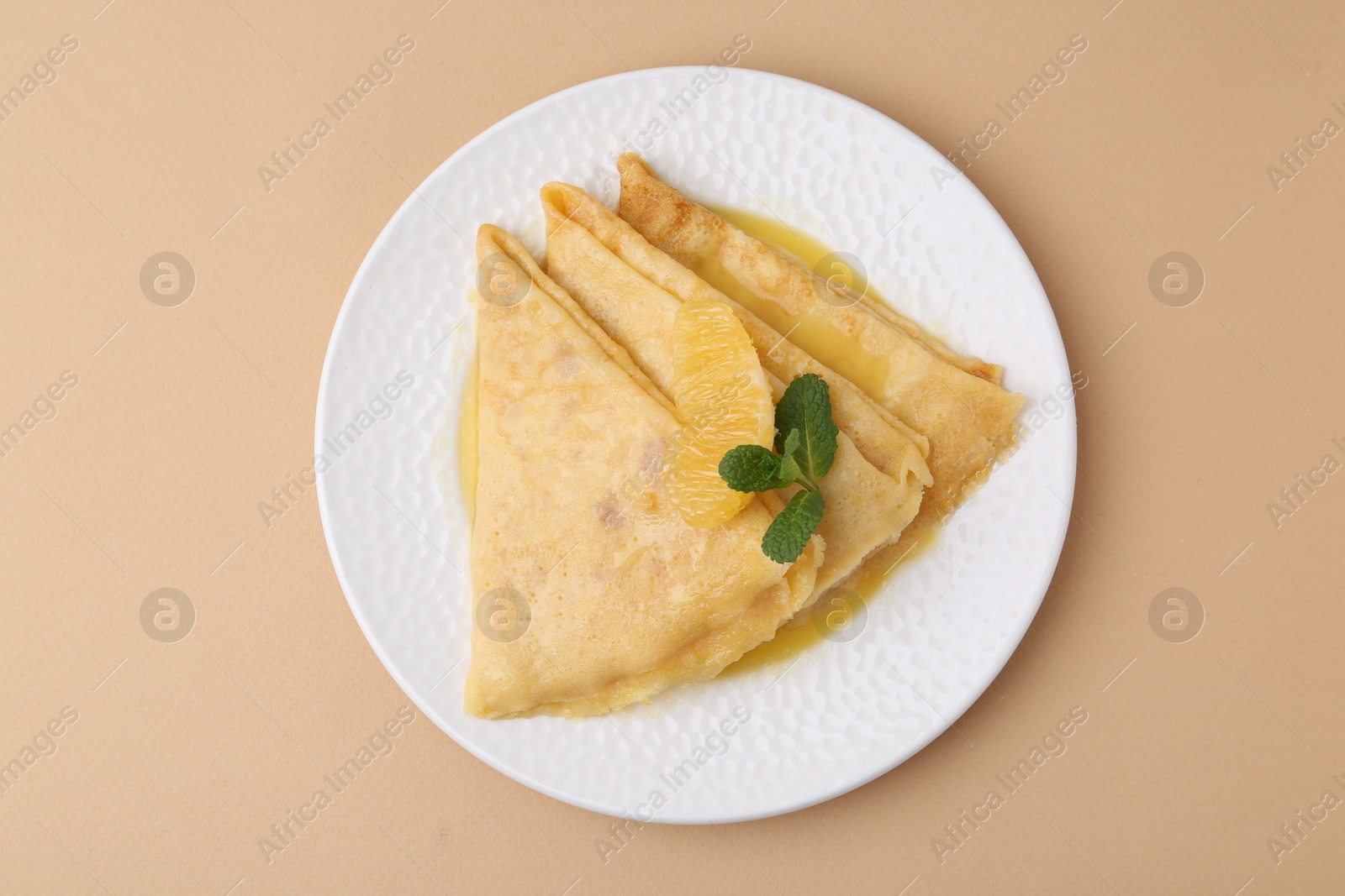 Photo of Plate with tasty crepes Suzette on beige table, top view