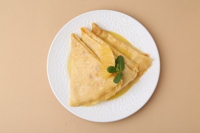 Photo of Plate with tasty crepes Suzette on beige table, top view