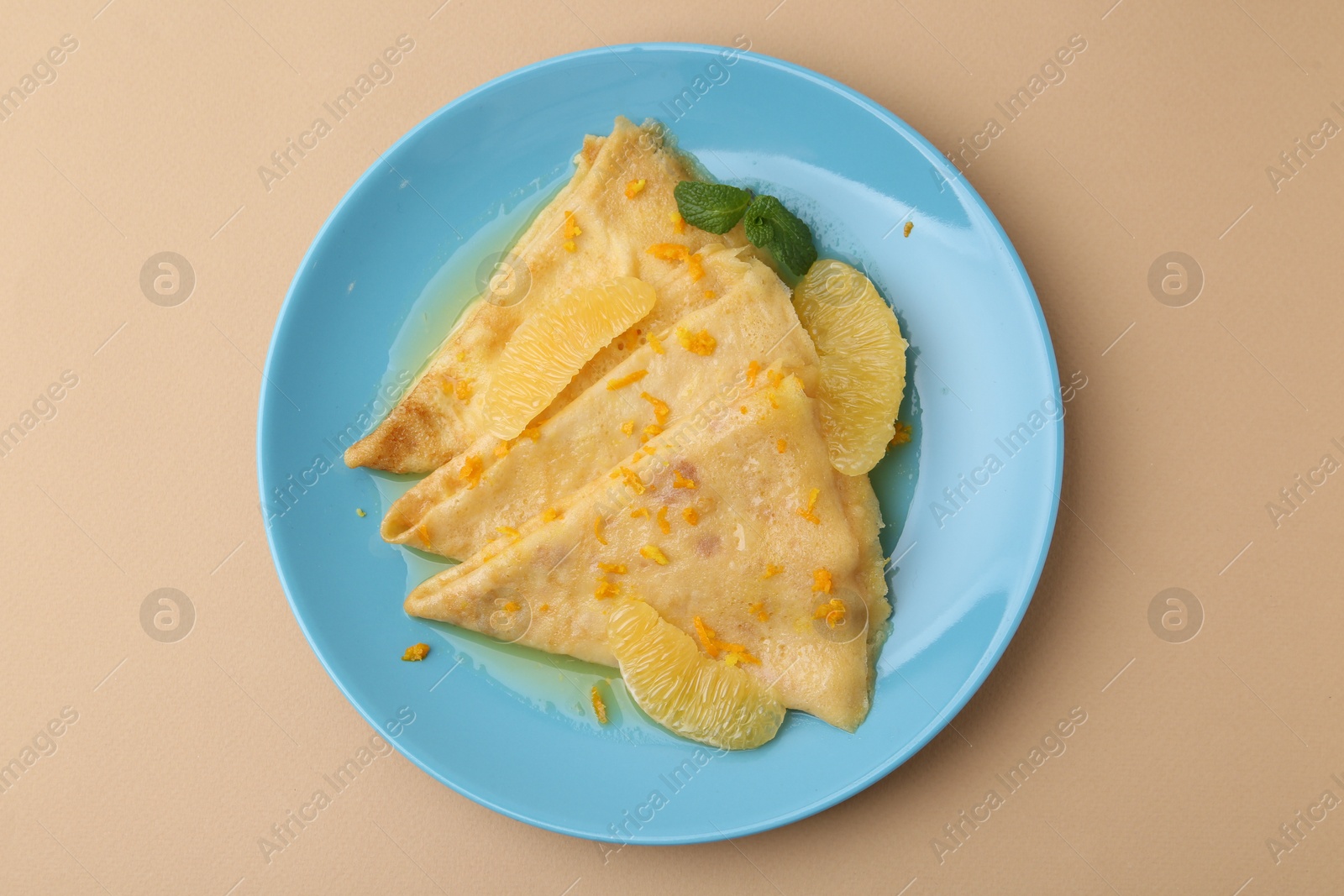 Photo of Plate with tasty crepes Suzette on beige table, top view