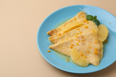 Photo of Plate with tasty crepes Suzette on beige table, closeup. Space for text