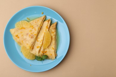 Photo of Plate with tasty crepes Suzette on beige table, top view. Space for text