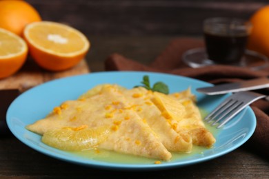 Photo of Plate with tasty crepes Suzette on wooden table, closeup