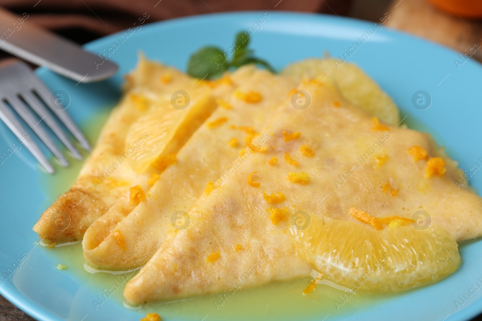 Photo of Plate with tasty crepes Suzette on table, closeup