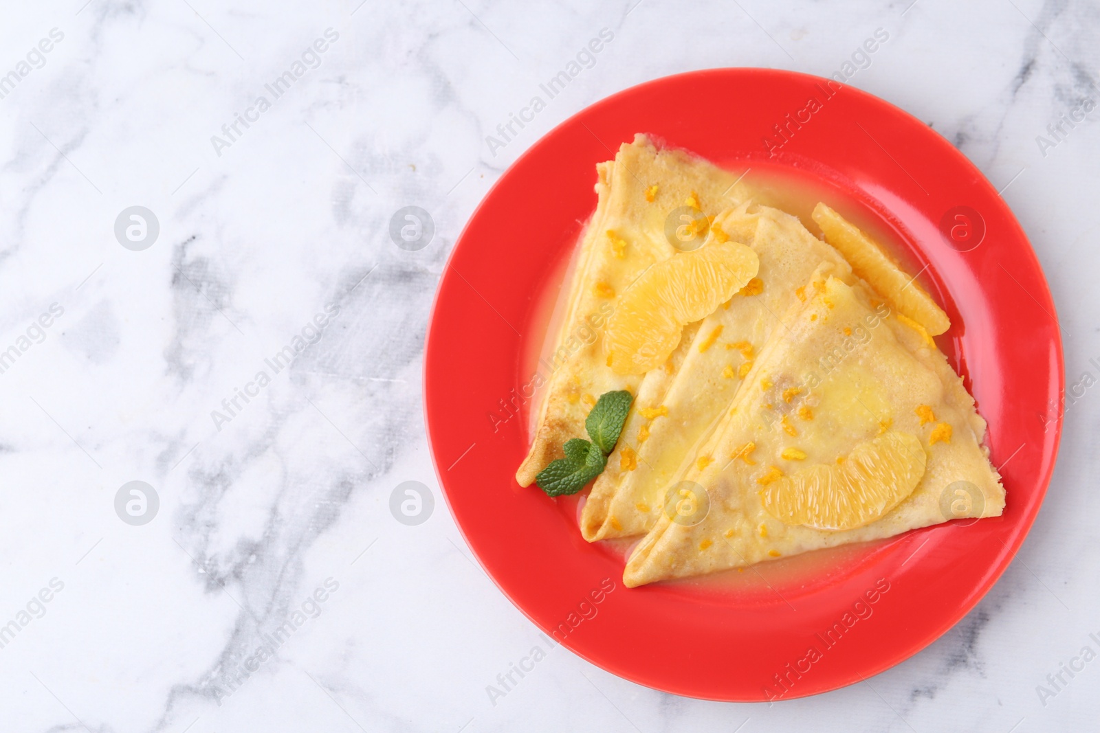 Photo of Plate with tasty crepes Suzette on white marble table, top view. Space for text