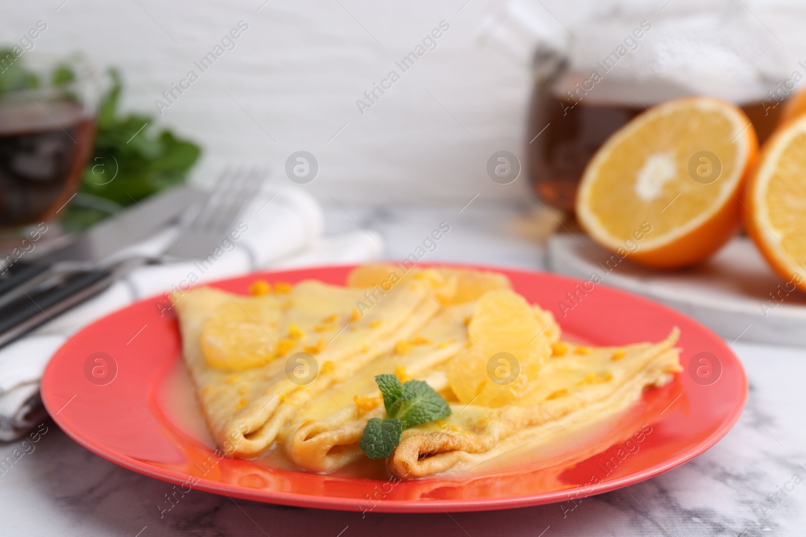 Photo of Plate with tasty crepes Suzette on white marble table, closeup