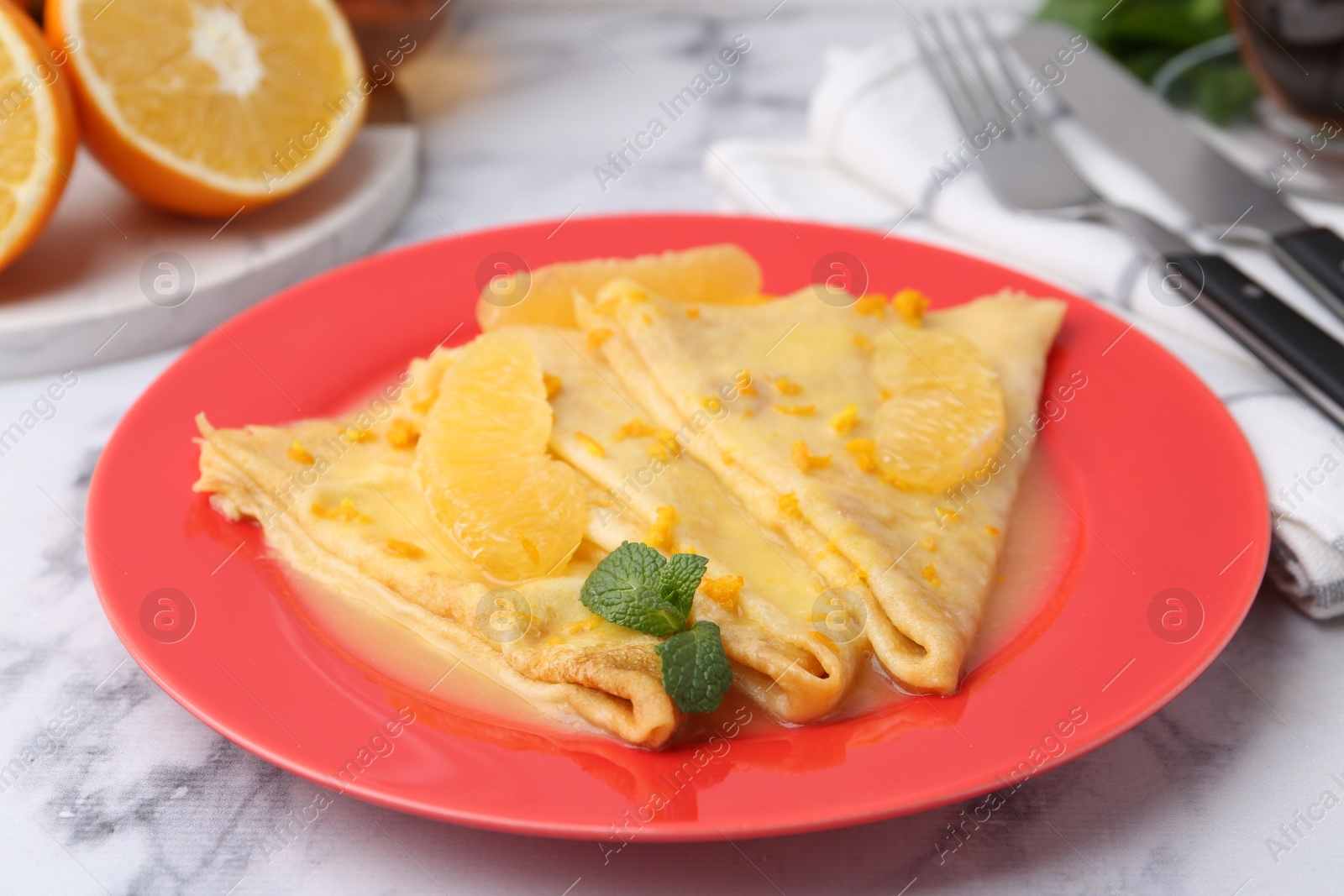 Photo of Plate with tasty crepes Suzette on white marble table, closeup