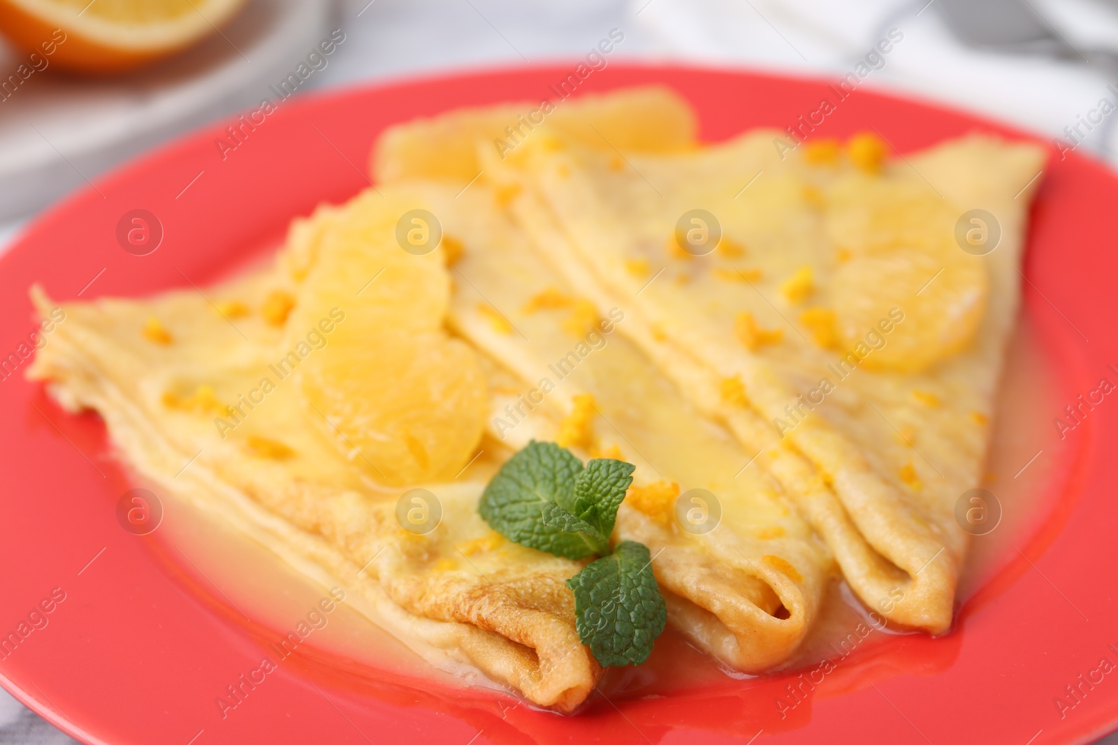 Photo of Plate with tasty crepes Suzette on table, closeup