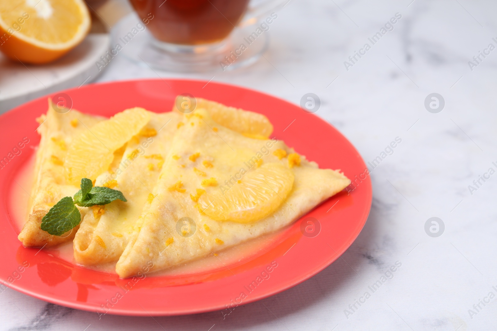 Photo of Plate with tasty crepes Suzette on white marble table, closeup. Space for text