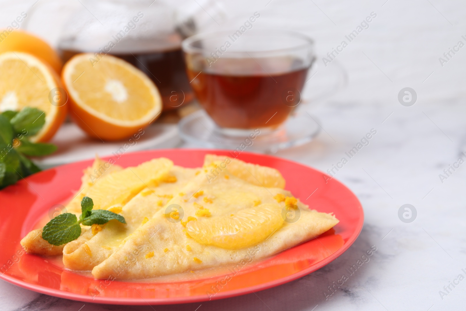 Photo of Plate with tasty crepes Suzette on white marble table, closeup