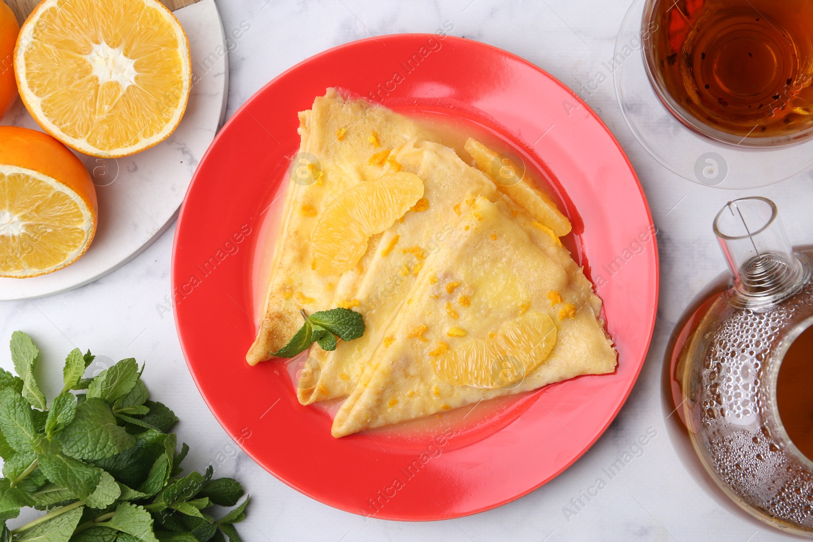 Photo of Tasty crepes Suzette served on white marble table, flat lay