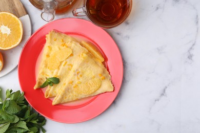 Photo of Tasty crepes Suzette served on white marble table, flat lay. Space for text