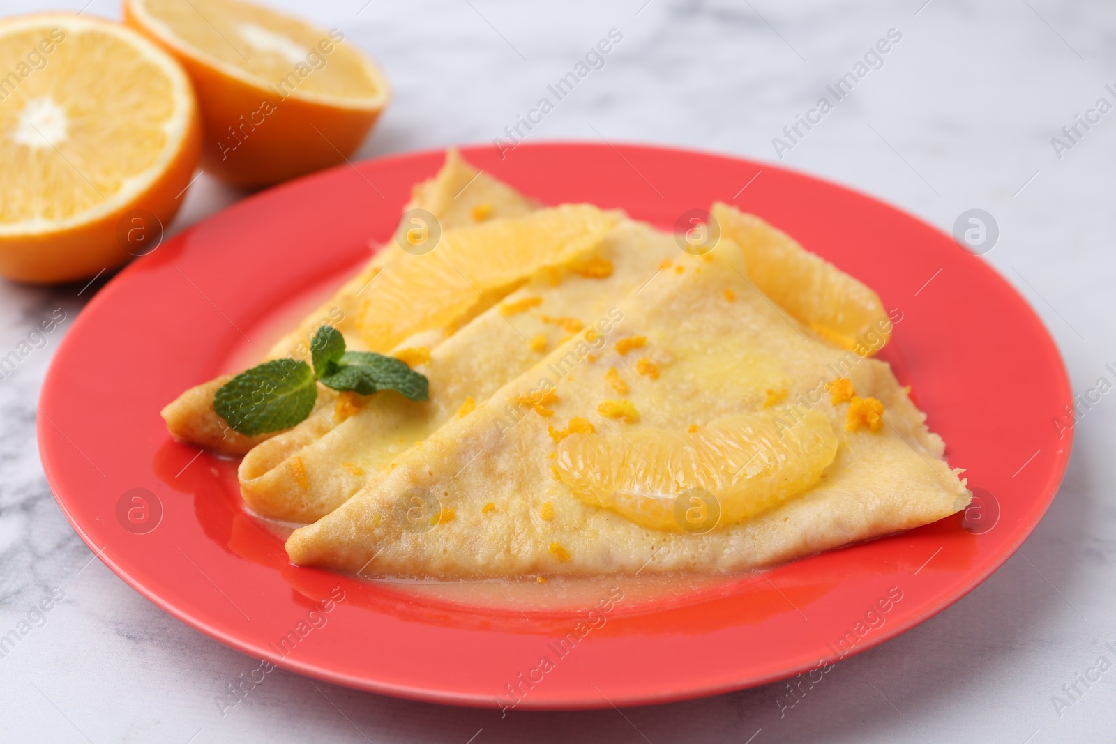 Photo of Plate with tasty crepes Suzette on white marble table, closeup