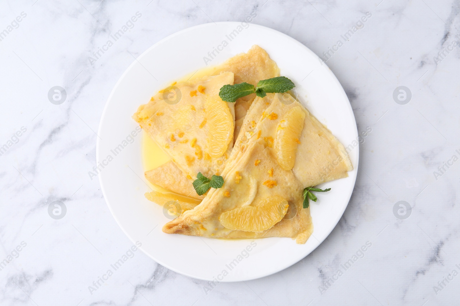 Photo of Plate with tasty crepes Suzette on white marble table, top view