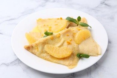 Photo of Plate with tasty crepes Suzette on white marble table, closeup