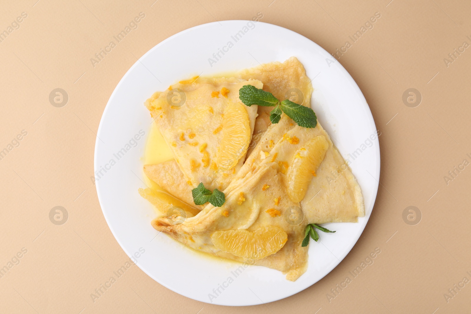 Photo of Plate with tasty crepes Suzette on beige table, top view