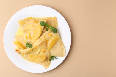 Photo of Plate with tasty crepes Suzette on beige table, top view. Space for text