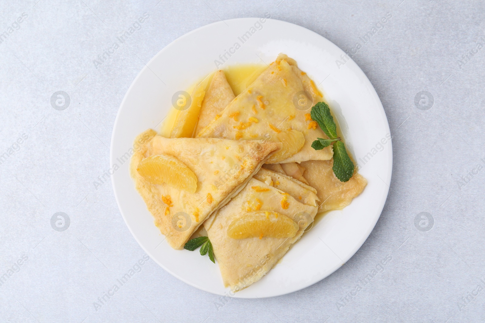 Photo of Plate with tasty crepes Suzette on light textured table, top view