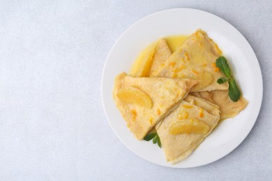 Photo of Plate with tasty crepes Suzette on light textured table, top view. Space for text