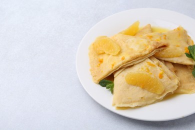 Photo of Plate with tasty crepes Suzette on light textured table, closeup. Space for text