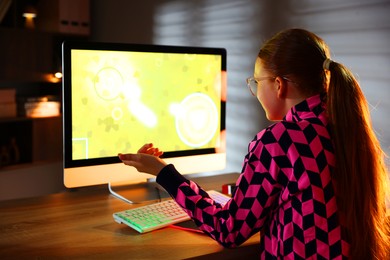 Photo of Girl playing video game with keyboard at table indoors