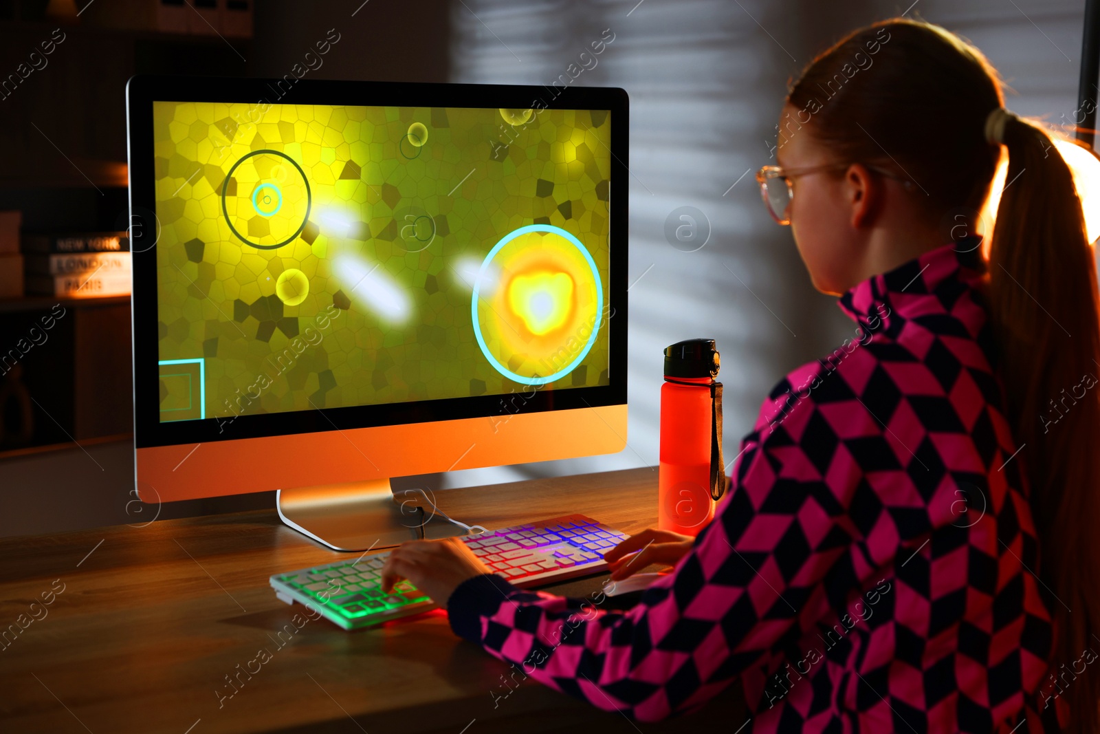 Photo of Girl playing video game with keyboard at table indoors