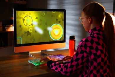 Photo of Girl playing video game with keyboard at table indoors