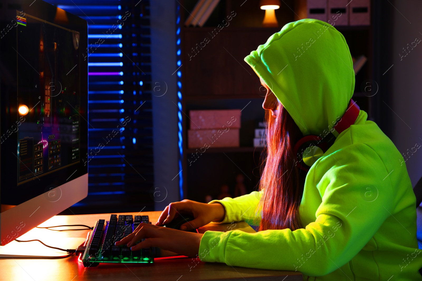 Photo of Girl playing video game with keyboard and mouse at table indoors