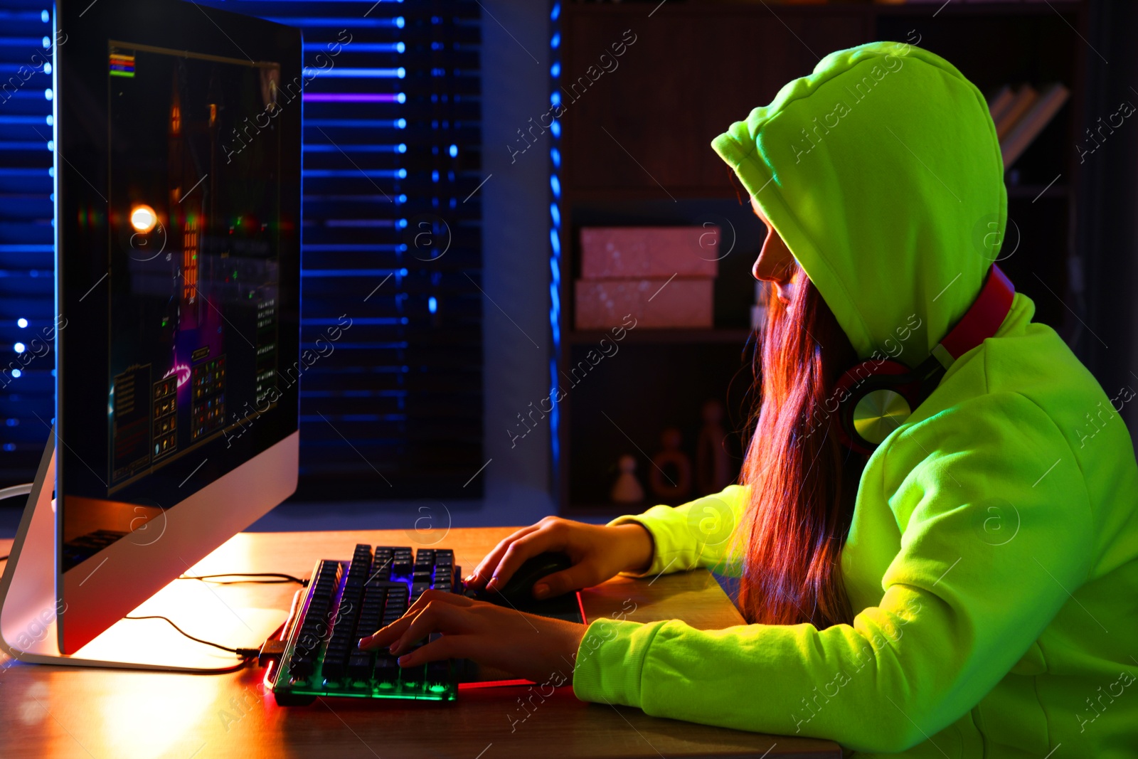 Photo of Girl playing video game with keyboard and mouse at table indoors