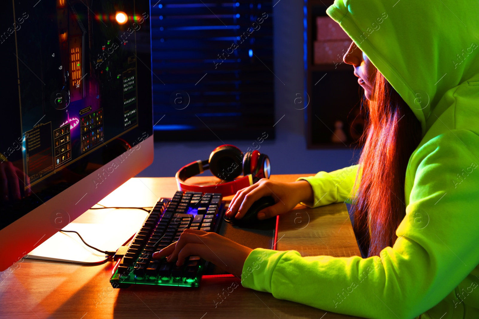 Photo of Girl playing video game with keyboard and mouse at table indoors