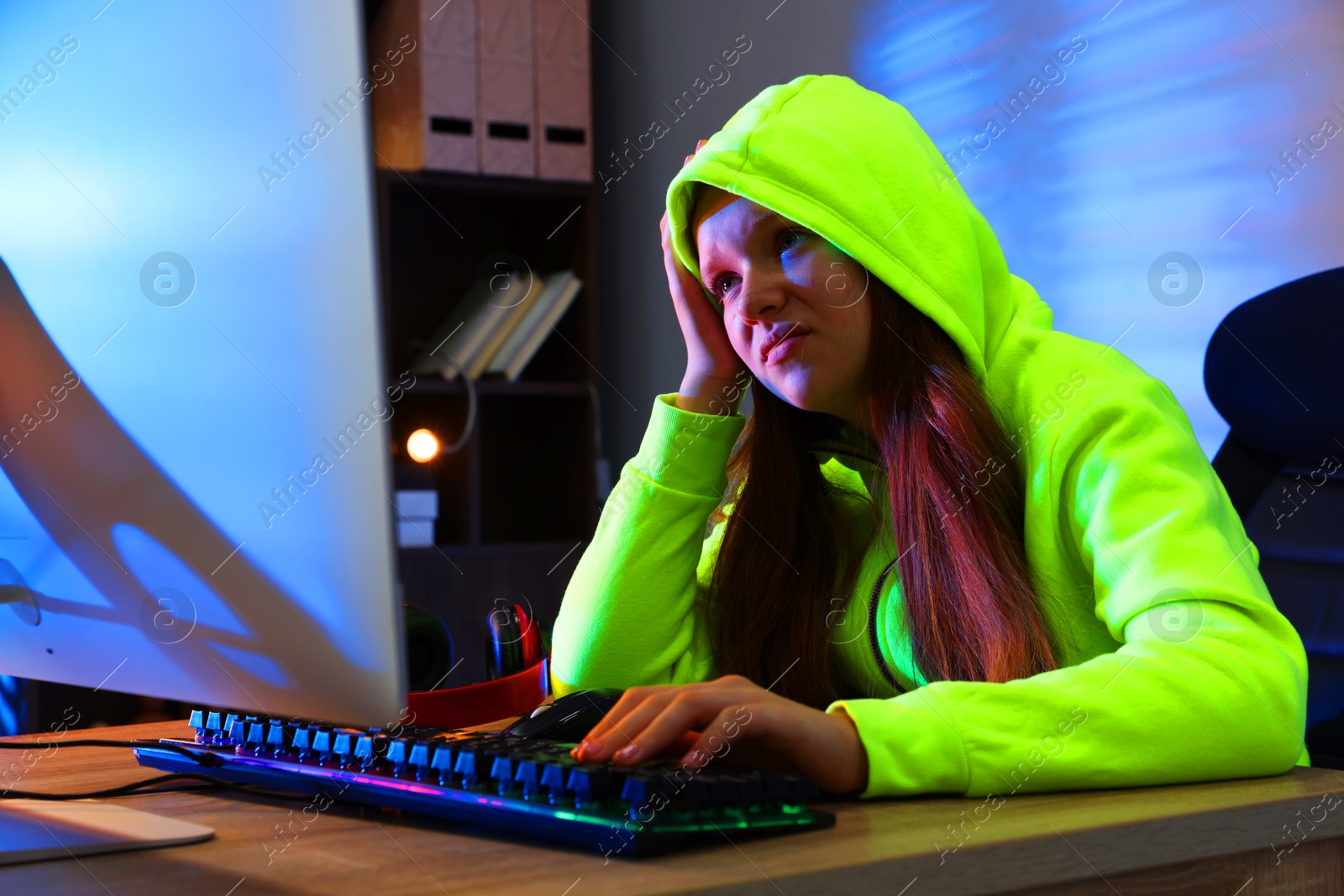 Photo of Girl playing video game with keyboard at table indoors