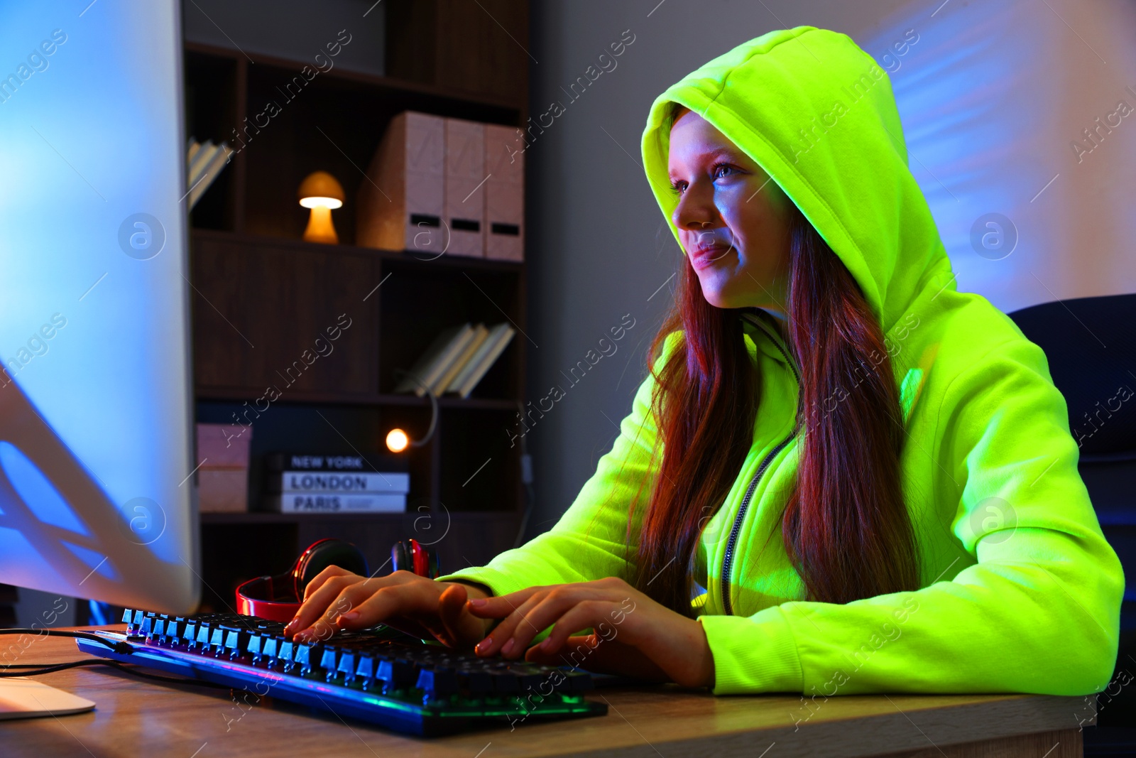 Photo of Girl playing video game with keyboard at table indoors