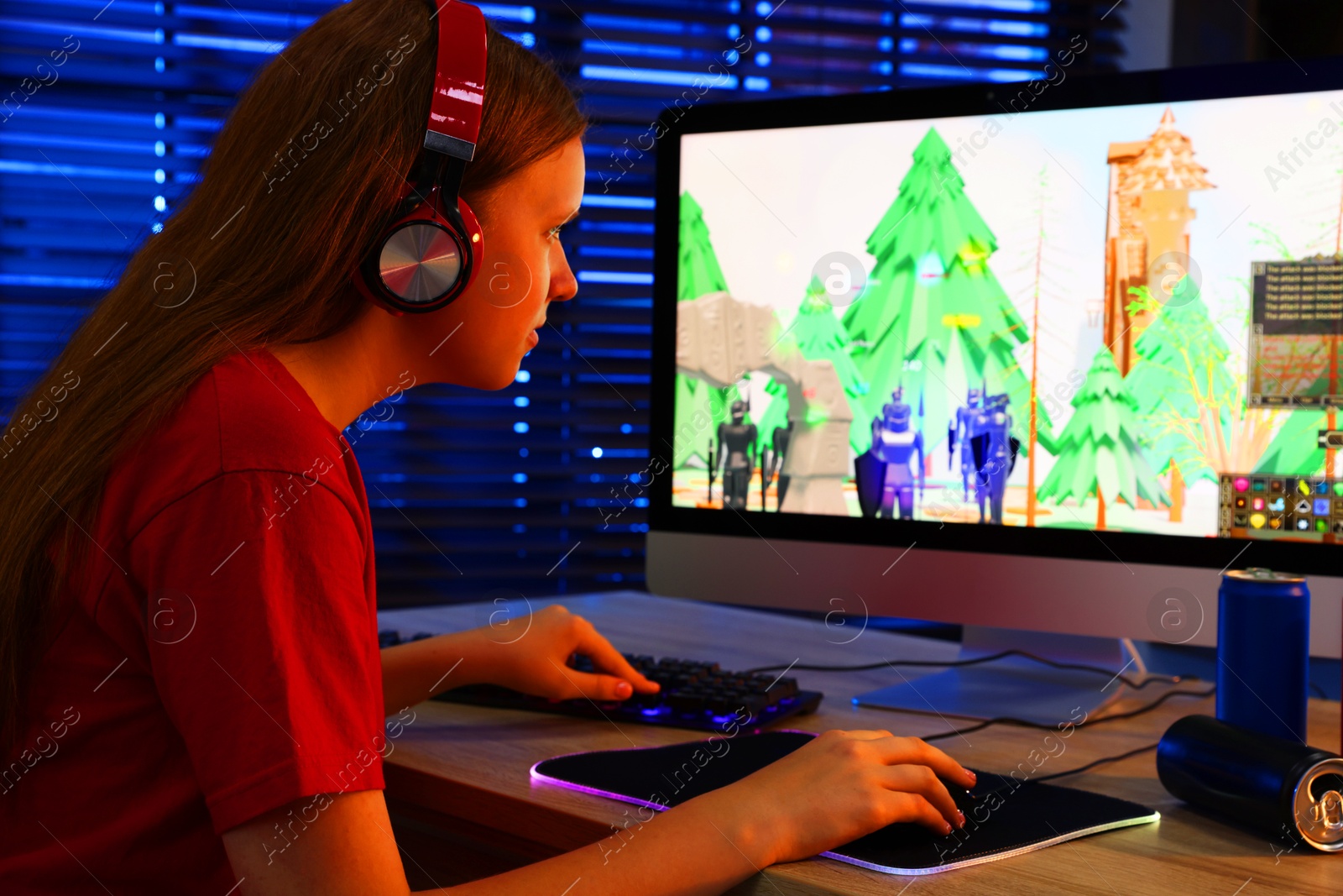 Photo of Girl playing video game with keyboard and mouse at table in dark room