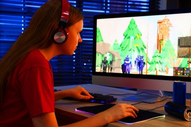 Photo of Girl playing video game with keyboard and mouse at table in dark room