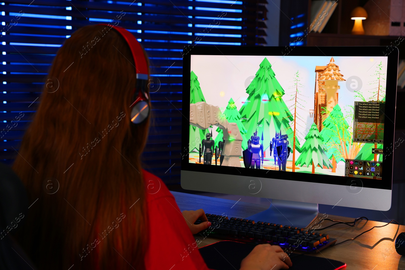 Photo of Girl playing video game with keyboard and mouse at table in dark room