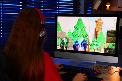 Photo of Girl playing video game with keyboard and mouse at table in dark room