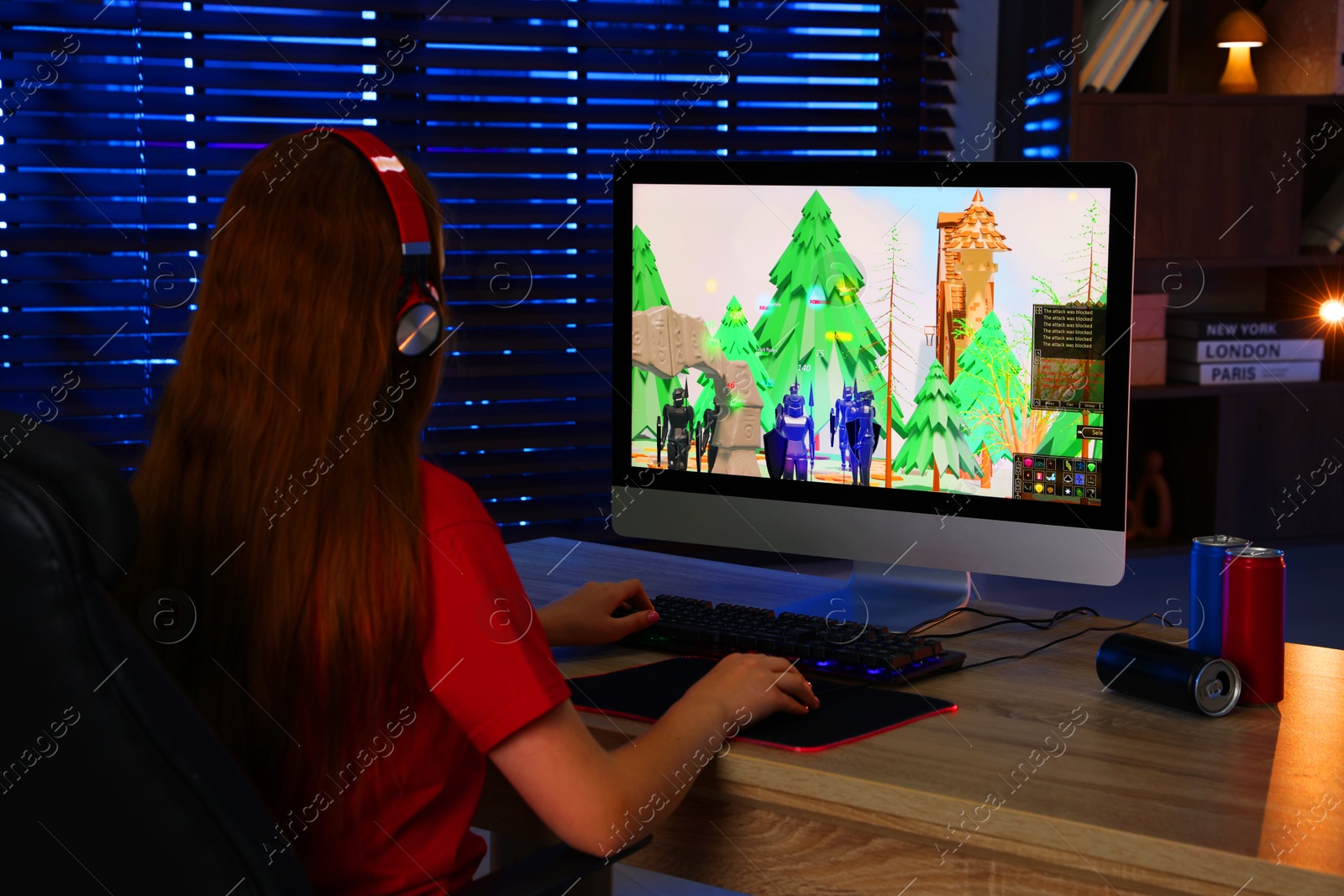 Photo of Girl playing video game with keyboard and mouse at table in dark room