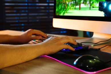 Photo of Young man using computer keyboard at wooden table indoors, closeup